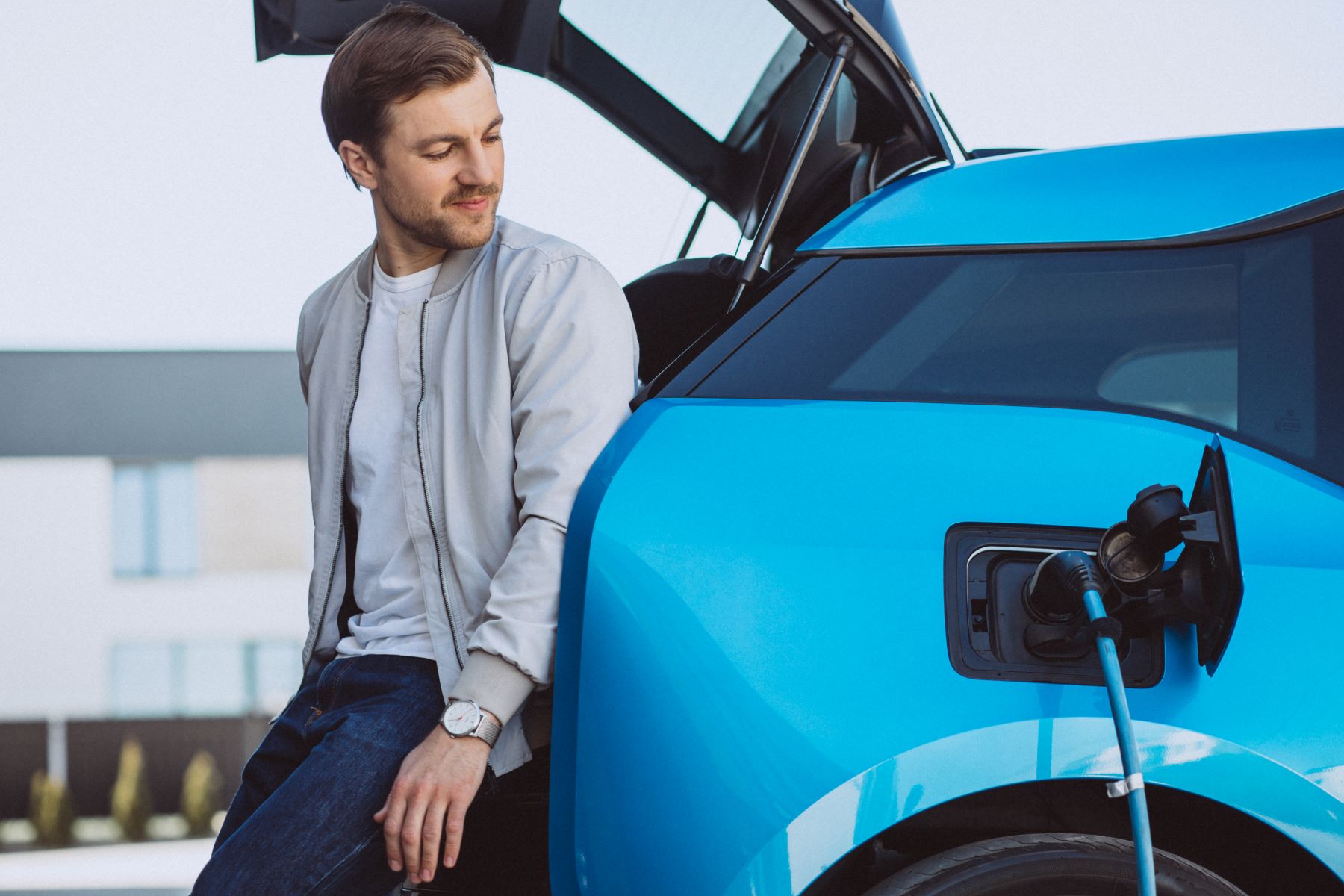 Business man standing besides car as it's charging