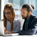two office people sharing laptop