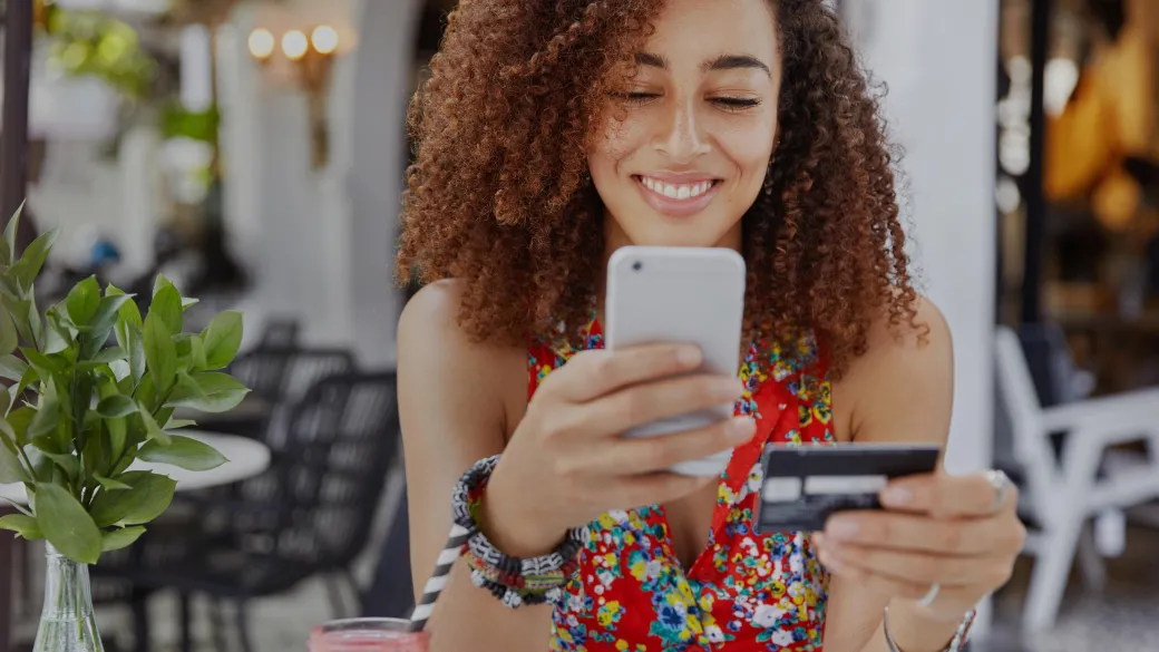 Junge Frau bei der Online-Zahlung auf einer Terrasse