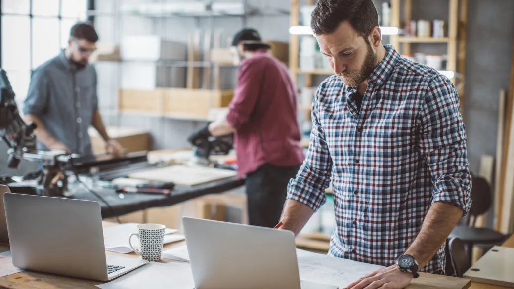man w/laptop in custom woodwork shop