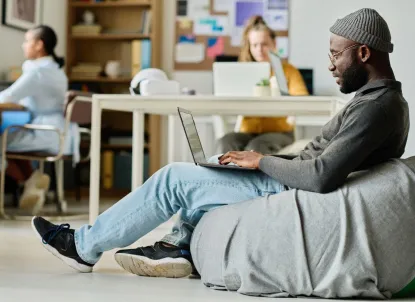 people omnichanel solutions man sitting comfortable bag chair working online laptop office