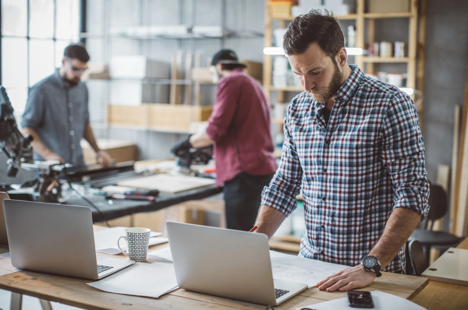 man w/laptop in custom woodwork shop