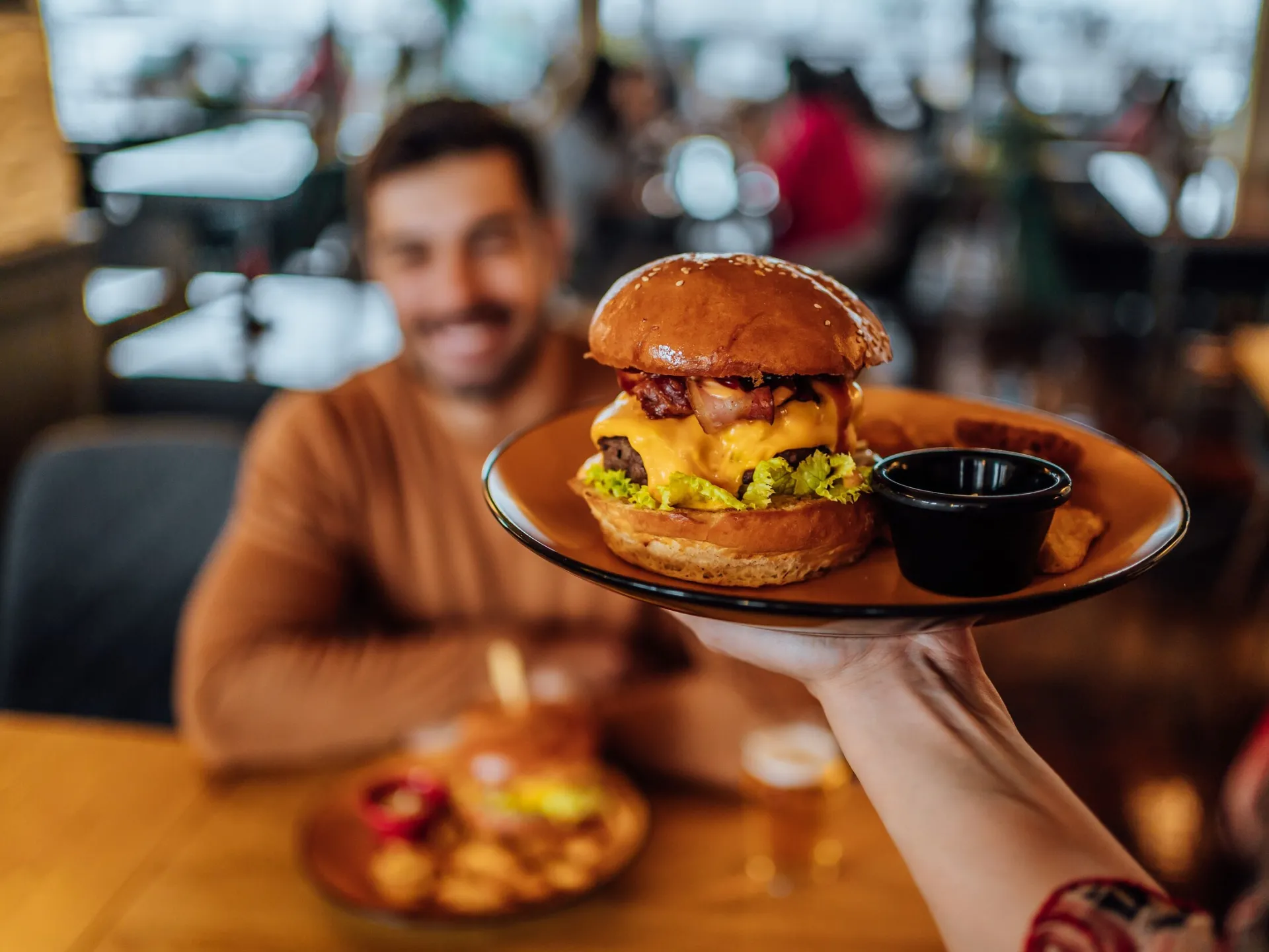 burger being delivered to man at table