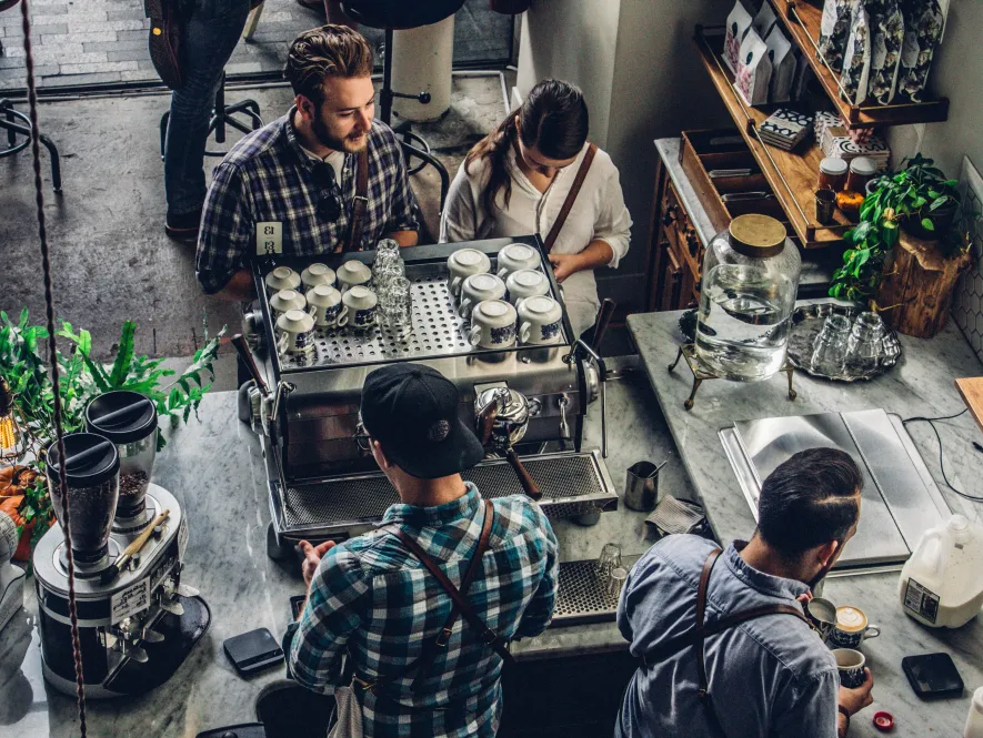 Customers at a coffee counter with baristas