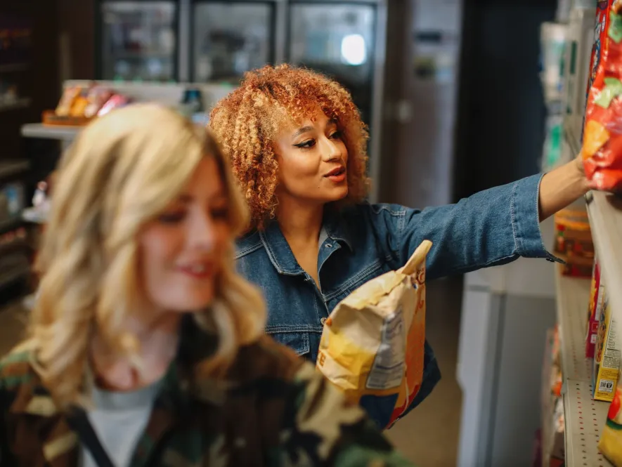 two young women in a convenience store selecting products