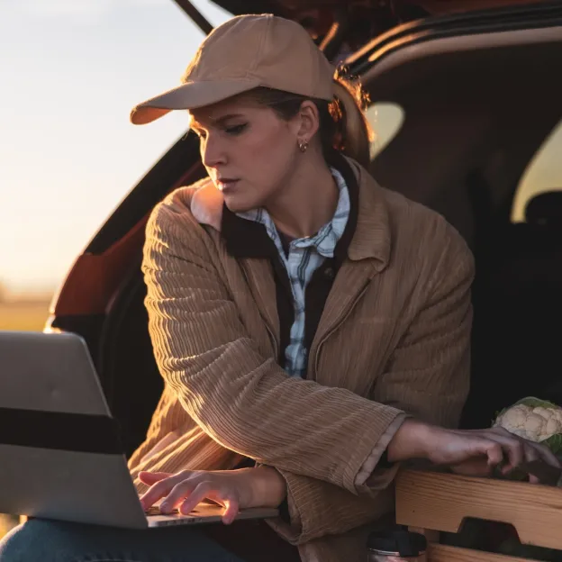 Woman with laptop on tailgate produce