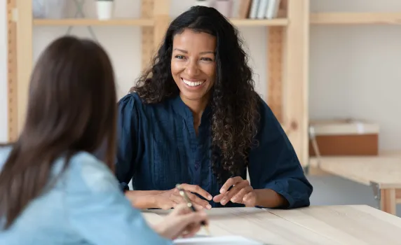 Two young women conversing at a modern work desk-counter