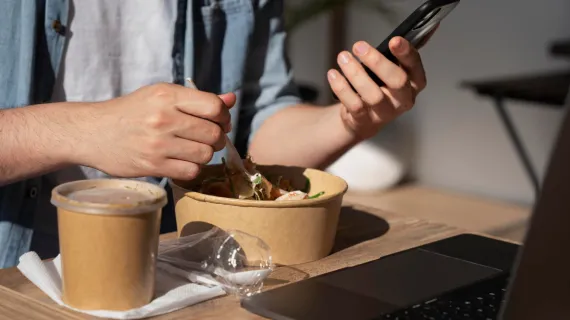 detail oline ordering man enjoying takeaway food using smartphone